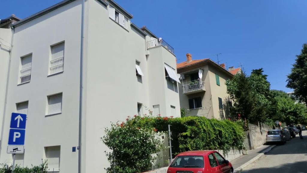 un edificio bianco con un'auto rossa parcheggiata accanto di Apartments Ružić a Spalato (Split)