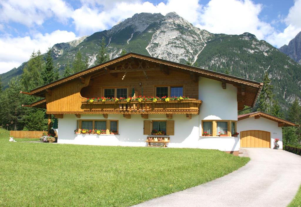 a house with a balcony with flowers in front of a mountain at Haus Schiefer in Leutasch