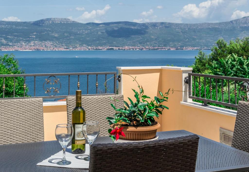 a table with wine glasses and a plant on a balcony at Apartment Leut with spacious terrace and sea view in Slatine