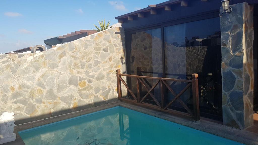 una casa con piscina accanto a un muro di pietra di villa martha a Yaiza