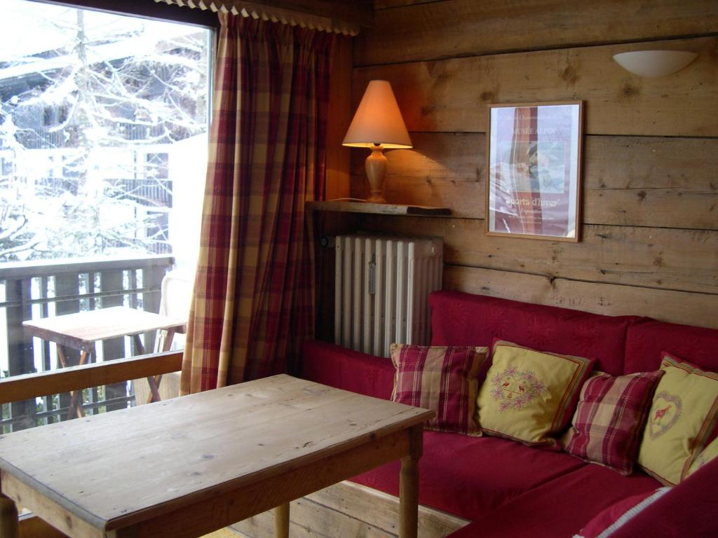 uma sala de estar com um sofá vermelho e uma mesa em Studio Les Drus / Studio du Brévent em Chamonix-Mont-Blanc