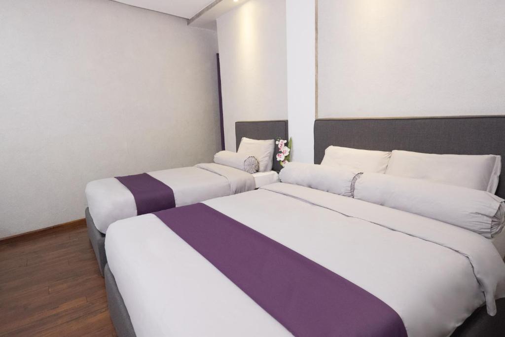 2 Betten in einem Zimmer mit Weiß- und Lilatönen in der Unterkunft Axiaa Hotel in Manila