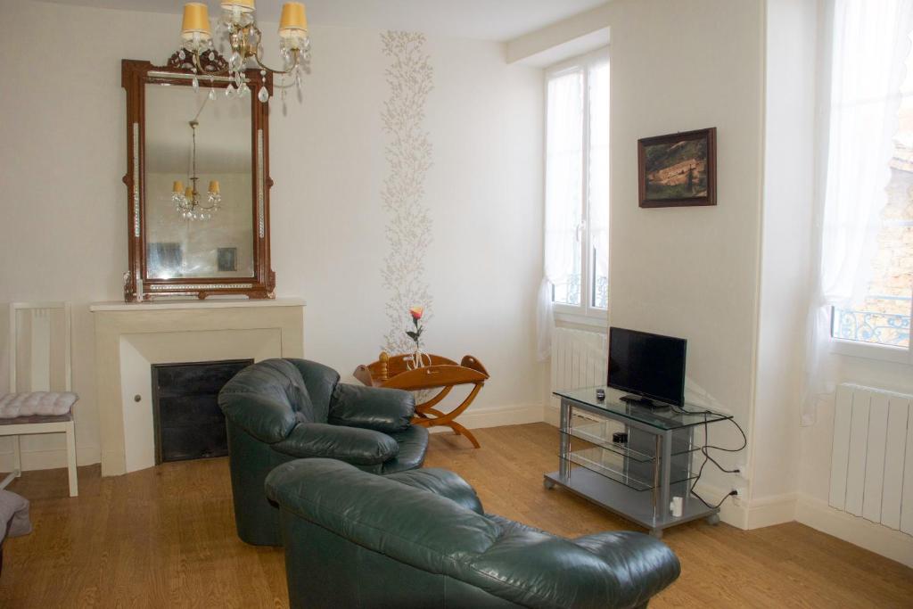 a living room with a green leather couch and a television at Les volets bleus in Melle