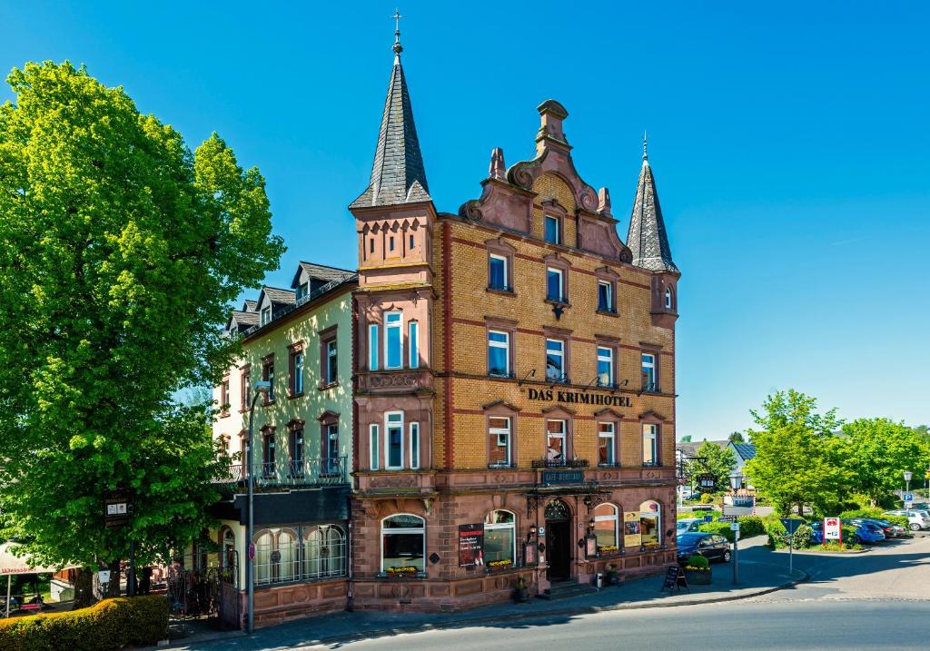 ein altes Backsteingebäude mit zwei Türmen auf einer Straße in der Unterkunft Das Krimihotel in Hillesheim