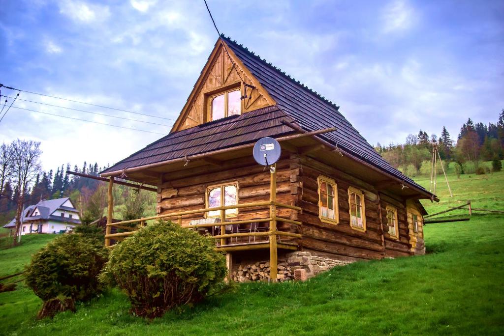 Cabaña de madera con techo en un campo verde en Domek Płazówka en Witów