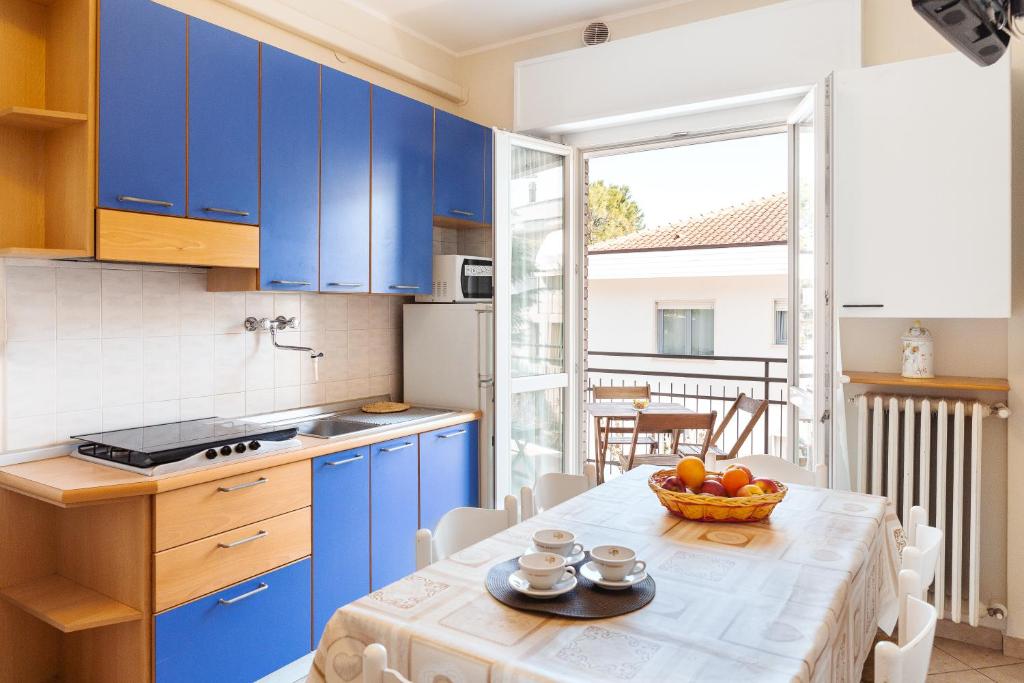 リッチョーネにあるVilla Maria Apartments nel Cuore di Riccioneのキッチン(青いキャビネット、フルーツボウル付きのテーブル付)