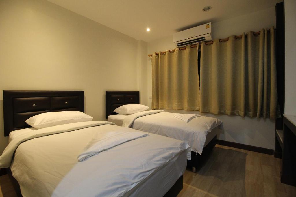 曼谷的住宿－採瓦旅舍，一间卧室设有两张床和窗户。