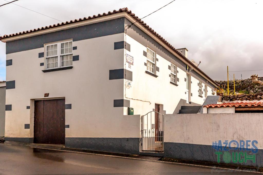 un bâtiment blanc avec une porte marron dans une rue dans l'établissement Casa do Tio Jose, à Doze Ribeiras