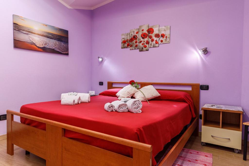 sypialnia z czerwonym łóżkiem i ręcznikami w obiekcie Rio Launaxi Guest House w mieście Teulada