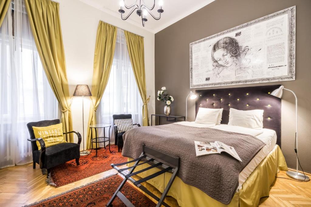 a bedroom with a large bed and a chair at Da Vinci Art Home in Budapest