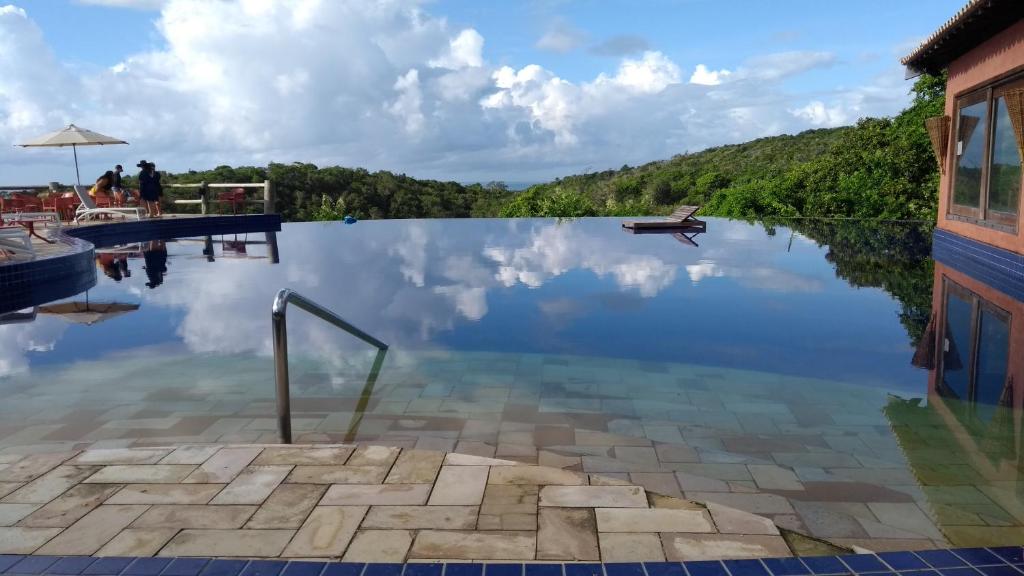 a pool with a reflection of the sky in the water at Bangalô no alto da colina no Villas do Pratagy - Maceió in Maceió
