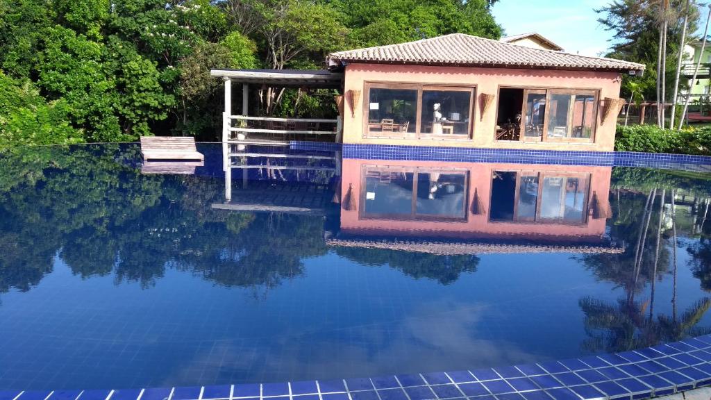 a house is reflected in the water of a swimming pool at Bangalô no alto da colina no Villas do Pratagy - Maceió in Maceió
