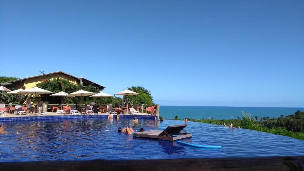 a pool at a resort with a chair in the water at Bangalô no alto da colina no Villas do Pratagy - Maceió in Maceió