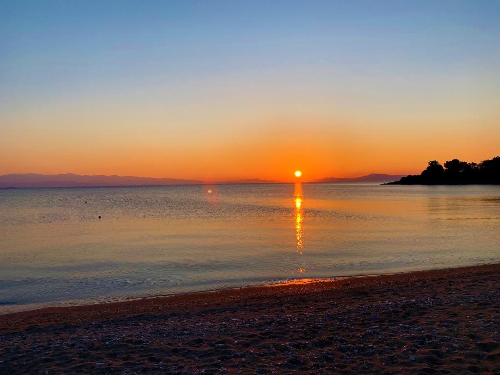 een zonsondergang op een strand met de zon in het water bij HORTO HOUSE in Chorto