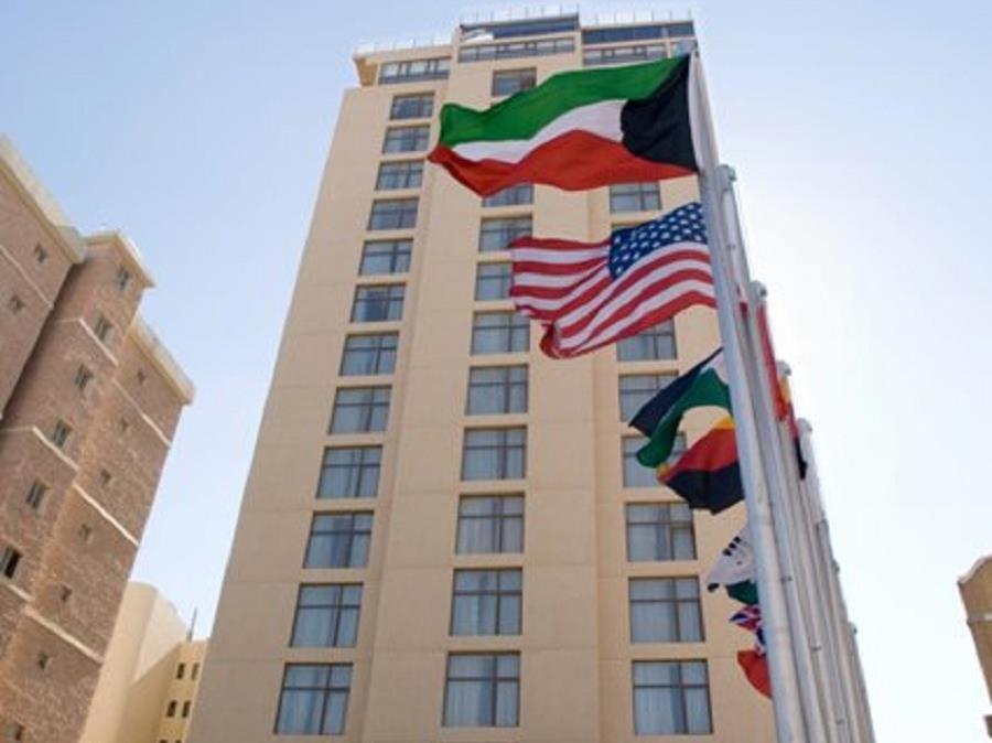 فندق لو جاز في الكويت: مبنى طويل مع أعلام أمامه