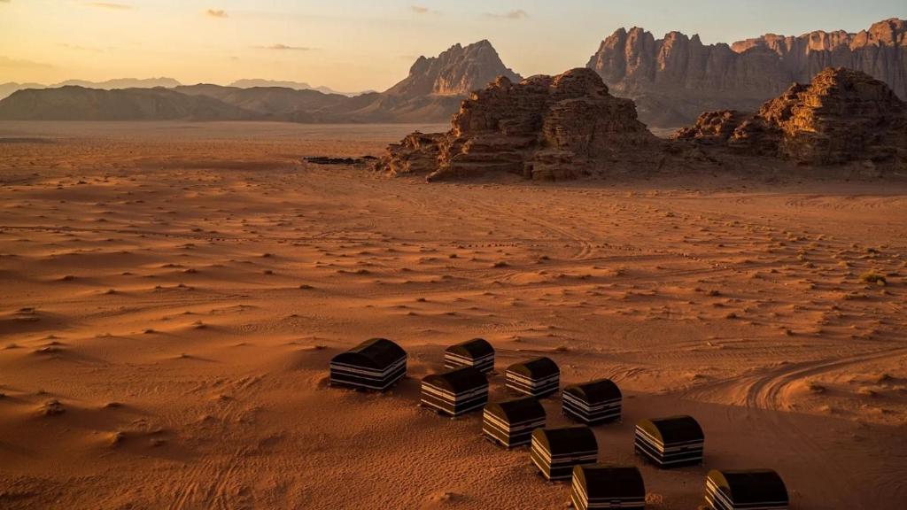 three beds in the desert with mountains in the background at Real Bedouin Experience Tours & Camp in Wadi Rum