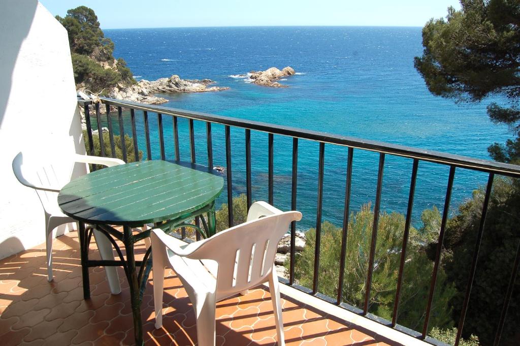 a table and chairs on a balcony with the ocean at STUDIOS FACE À LA MER - Cala Llevado in Tossa de Mar