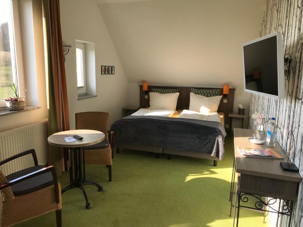 a bedroom with a bed and a table and a television at Pension Freudenthal in Wandersleben