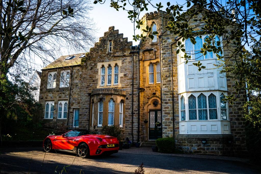 a red car parked in front of a building at Farnley Tower Guesthouse in Durham