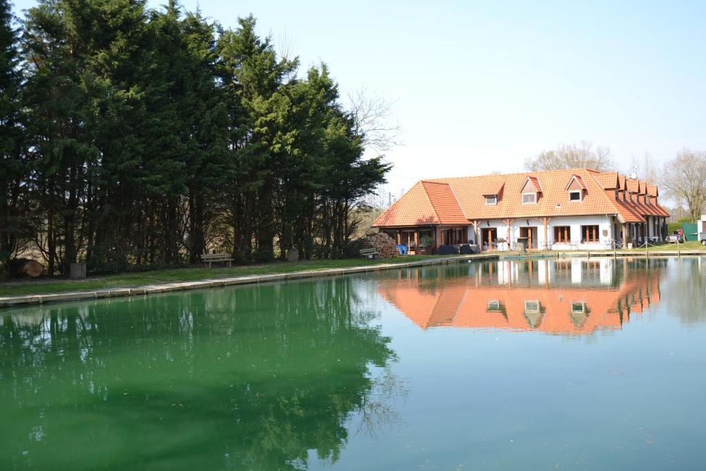 une maison assise à côté d'une grande étendue d'eau dans l'établissement Les Étangs des Couartes, à Saint-Josse