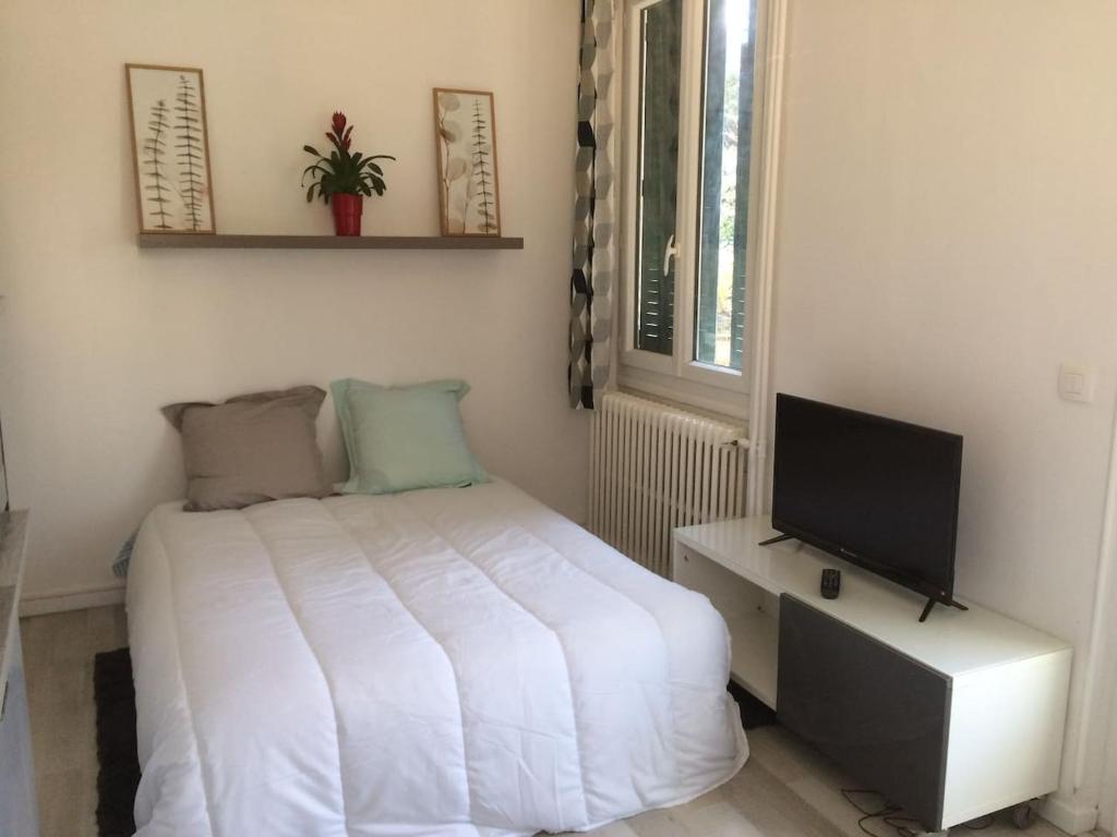 a bedroom with a white bed and a television at Studio Bassens in Bassens