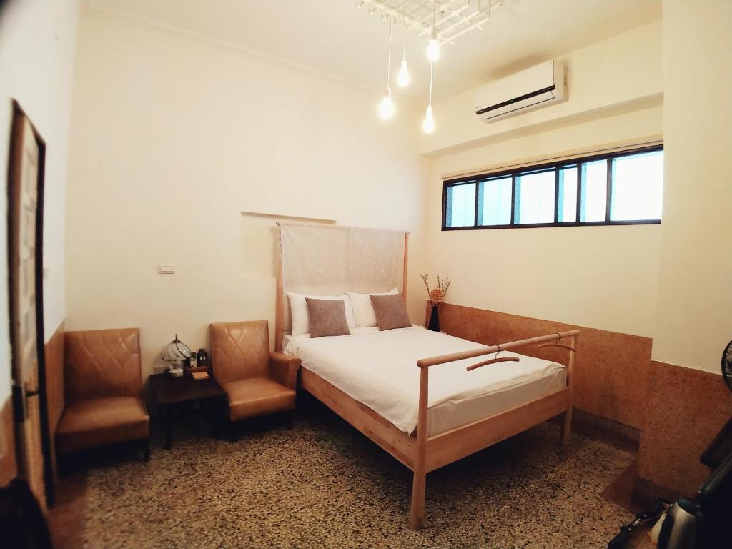 una camera da letto con un letto e una sedia di GOIN Old House & Bar a Tainan