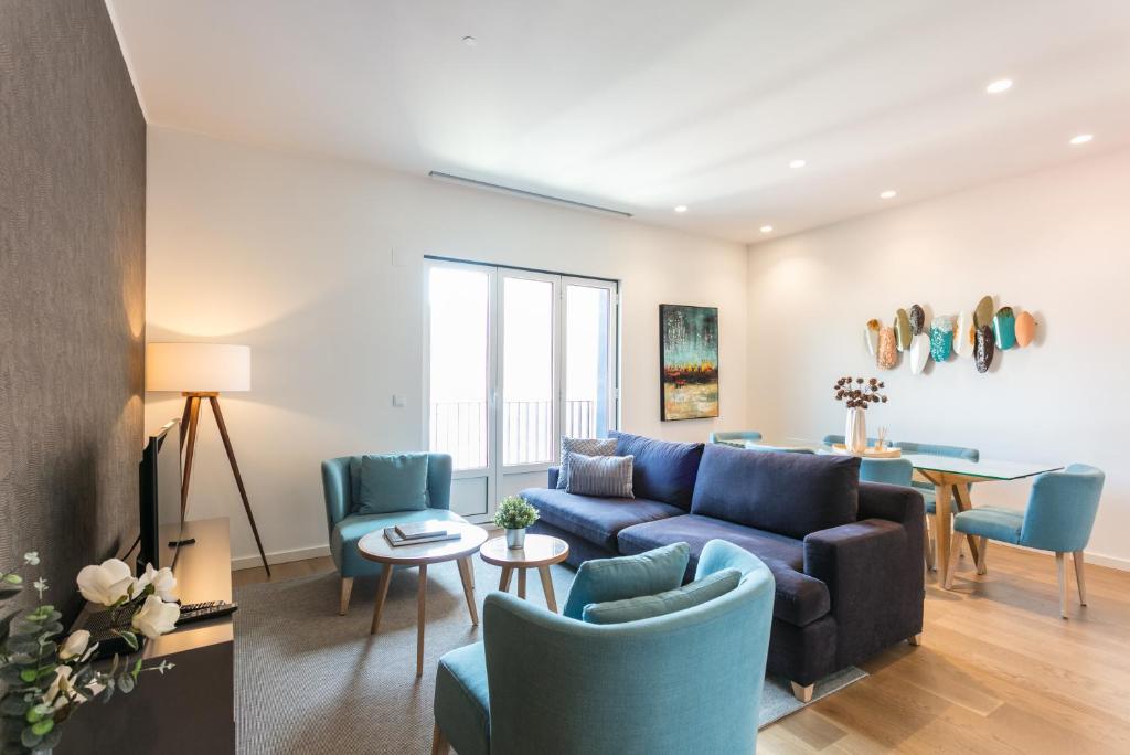 een woonkamer met een blauwe bank en stoelen bij FLH Restauradores Modern Apartment in Lissabon