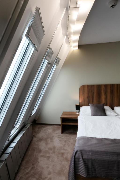 a bedroom with a bed and two windows at Hotel Ještěd in Liberec