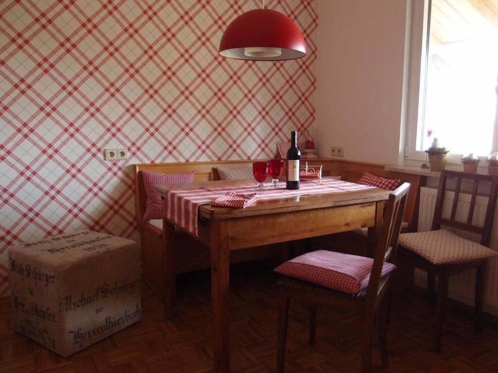Ferienwohnung Wohnsiedler في Rot am See: طاولة غرفة طعام مع زجاجة من النبيذ وكرسيين