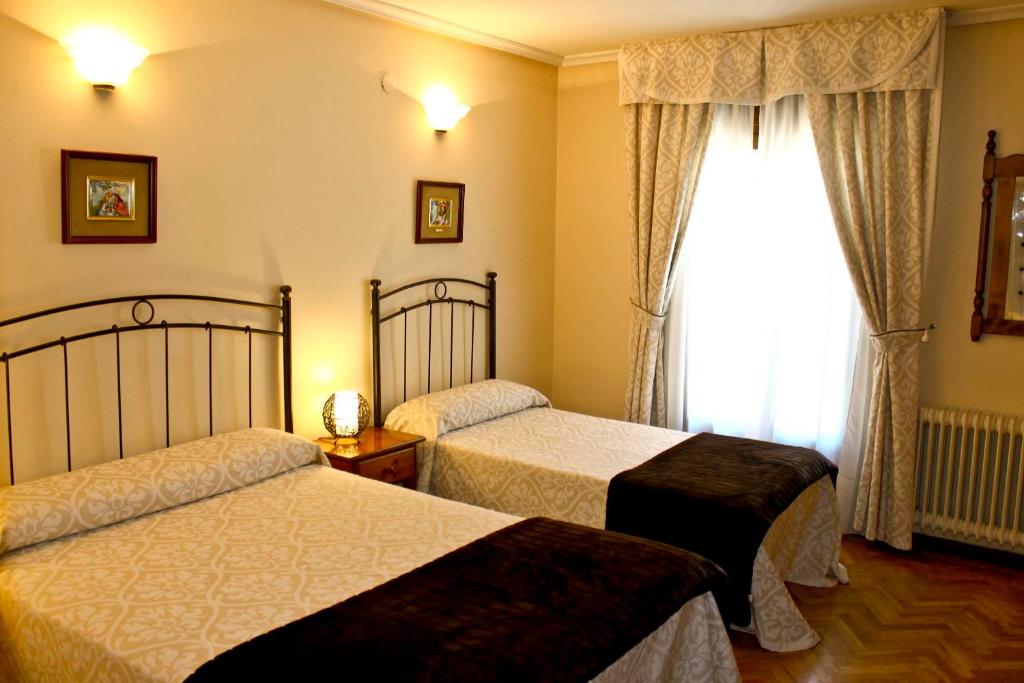 a hotel room with two beds and a window at Hostal Alcántara in Ávila