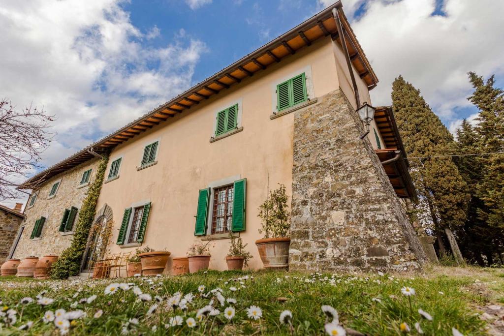 ein altes Steingebäude mit grünen Fensterläden und Blumen in der Unterkunft Fattoria Poggio di Fiesole in Fiesole
