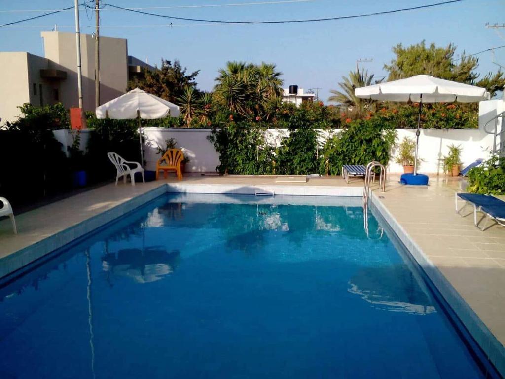 a large blue swimming pool with chairs and umbrellas at Villas Irene 5 Family Apartments in Kokkíni Khánion