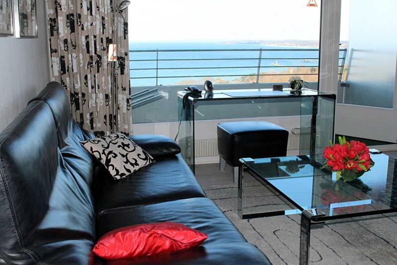 ein Wohnzimmer mit einem schwarzen Ledersofa und einem Glastisch in der Unterkunft Apartmentvermittlung Mehr als Meer - Objekt 4 in Timmendorfer Strand