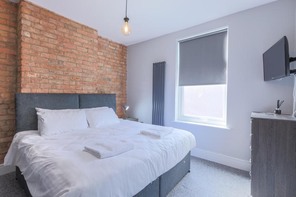 朗伊頓的住宿－Salisbury Street Guesthouse，一间卧室设有一张带砖墙的大床