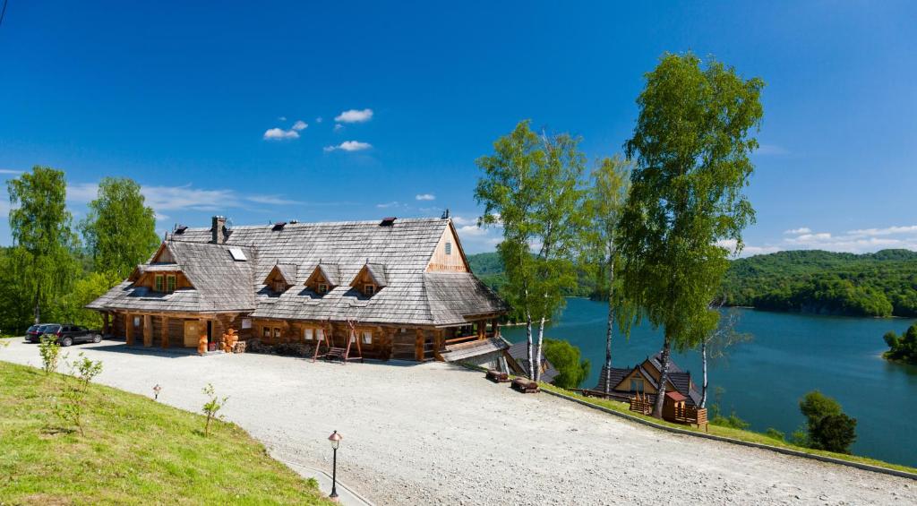 une grande maison en bois sur le côté d'un lac dans l'établissement Ostoja Spokoju, à Olchowiec