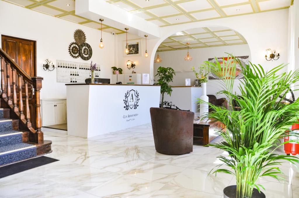 een lobby met potplanten en een bar bij Hôtel les Arbousiers in Calvi