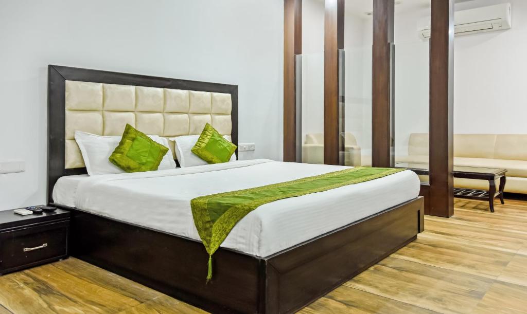 1 dormitorio con 1 cama grande con almohadas verdes en Treebo Trend Red Petal Jalandhar en Jalandhar