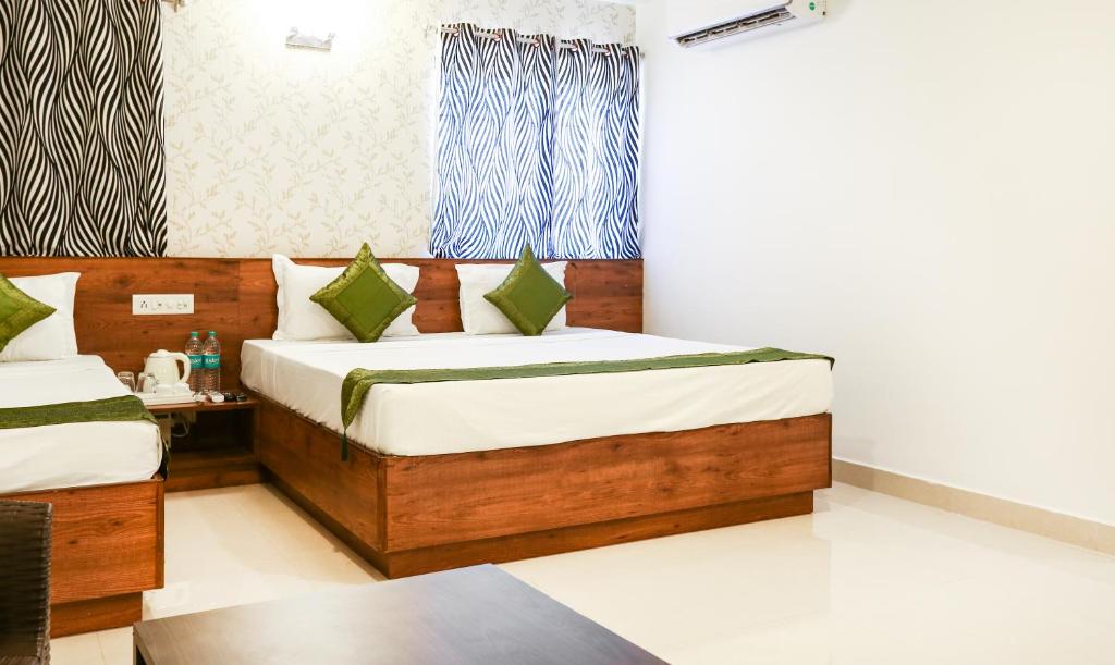 Itsy By Treebo - Comforts Inn, University Road Deralakatte في منغالور: غرفة نوم بسريرين وطاولة في غرفة