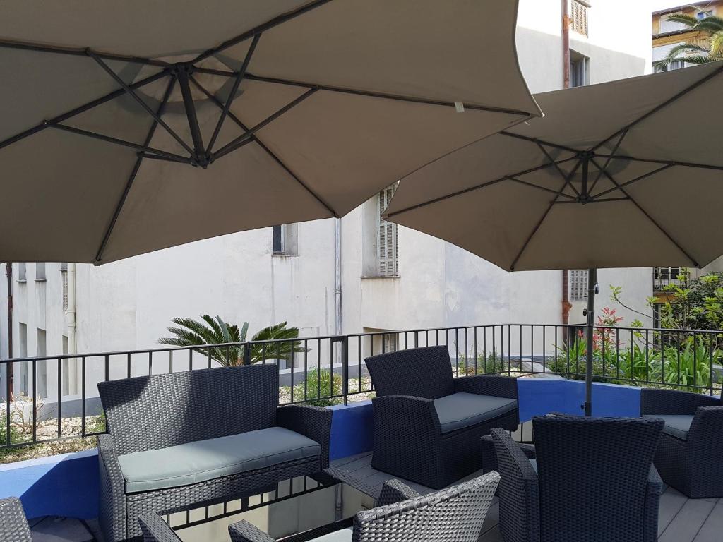a patio area with chairs and umbrellas at Hôtel les Cigales in Nice