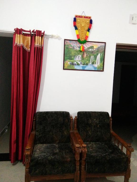 a living room with two chairs and a curtain at Nunu Homestay Guruvayoor in Guruvāyūr