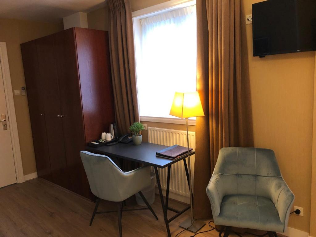 a room with a desk and a chair and a window at Hotel Johannes Vermeer Delft in Delft