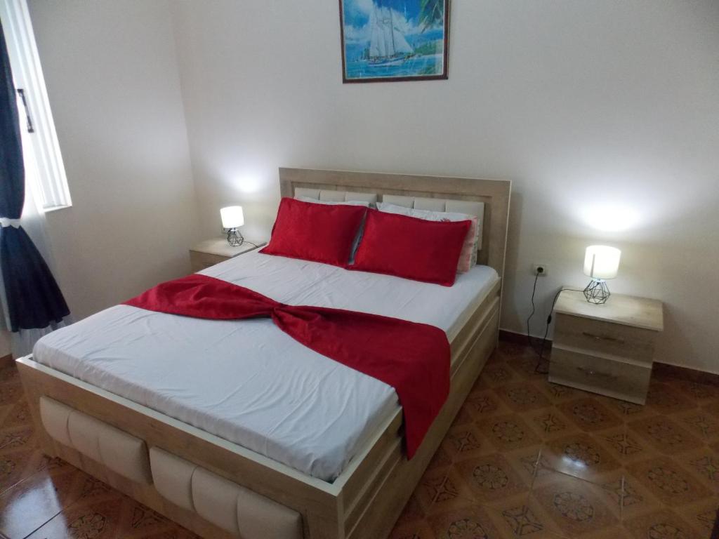 1 dormitorio con 1 cama grande con almohadas rojas en Apartment Dejvi, en Sarandë