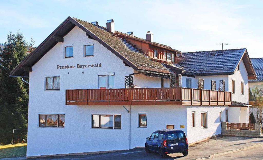 a blue car parked in front of a white house at Pension "Bayerwald" in Frauenau