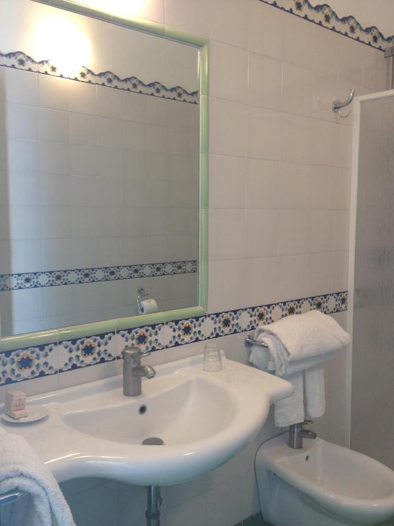 a bathroom with a sink and a mirror and a toilet at Hotel Aura in Vulcano
