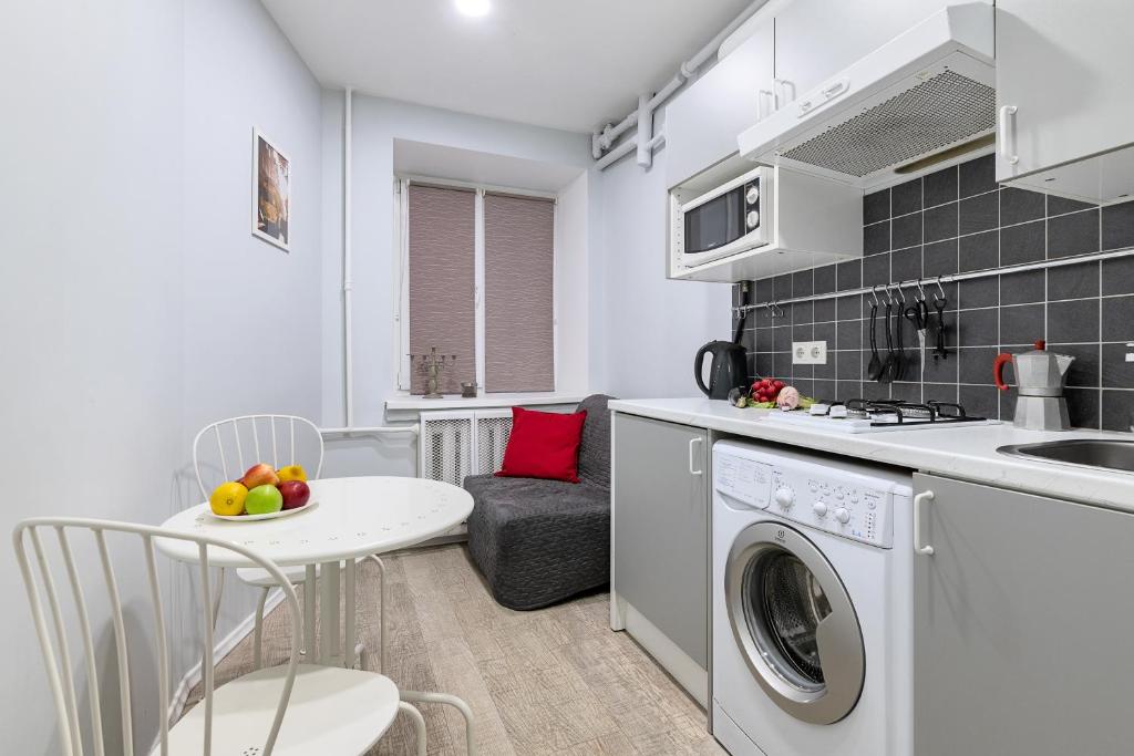 uma cozinha com uma máquina de lavar roupa e uma mesa com uma taça de fruta em RentalSPb with Private entrance em São Petersburgo