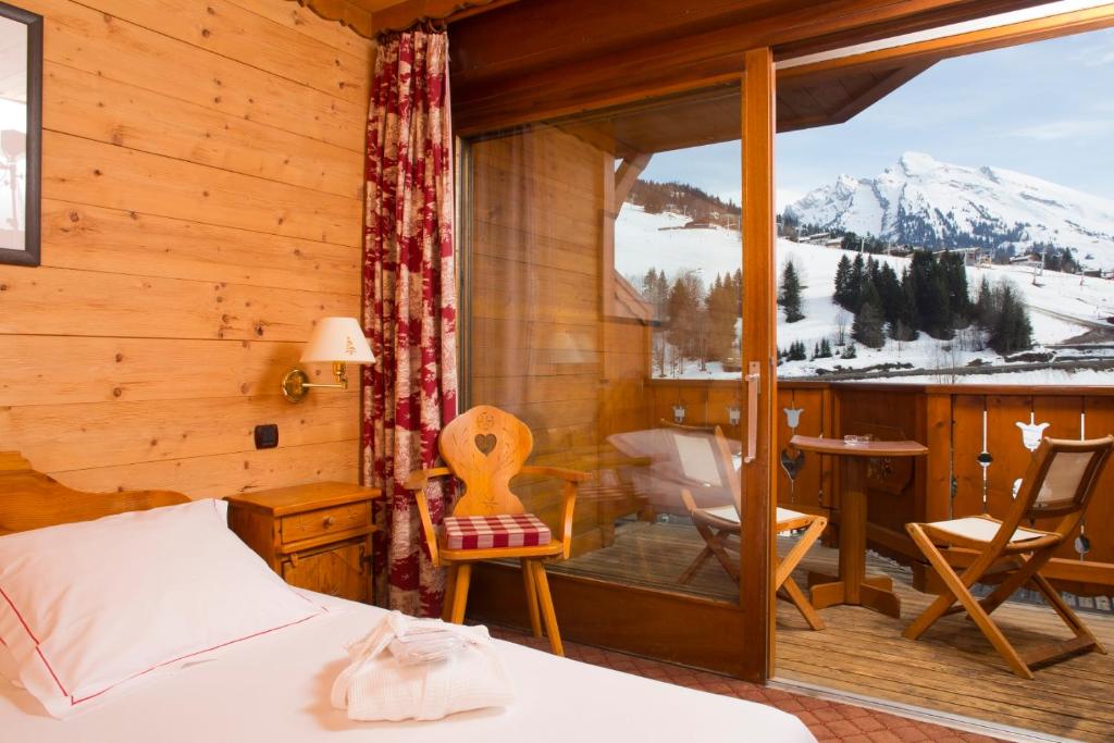 a bedroom with a bed and a balcony with a view at Carlina in La Clusaz