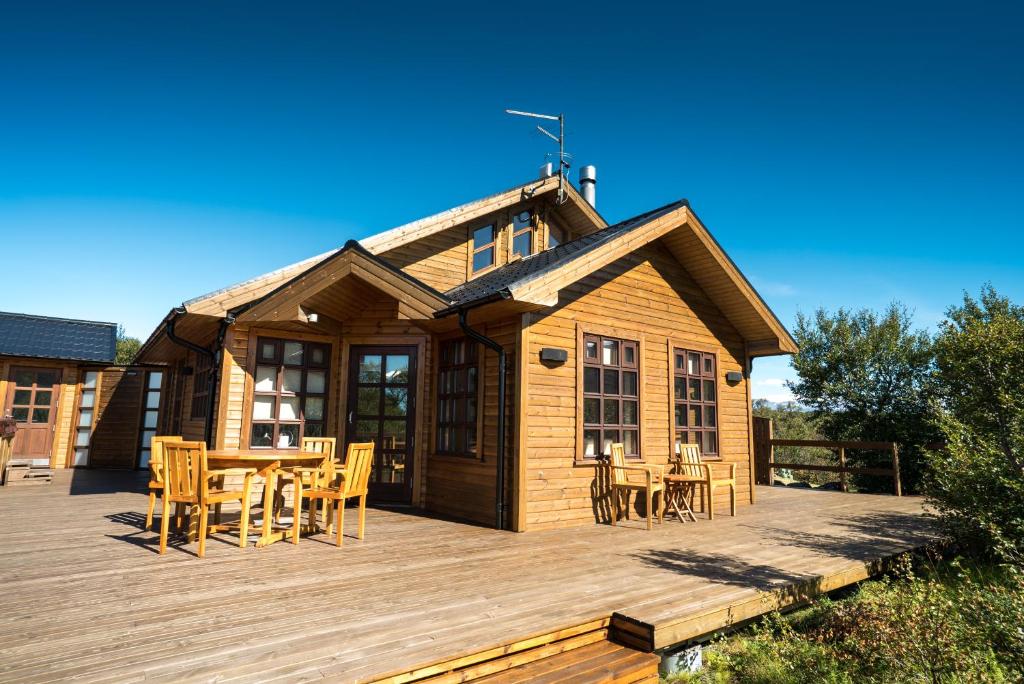 a house with a deck with a table and chairs at Húsafell holiday homes in Húsafell