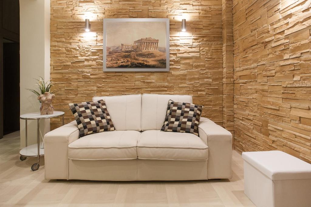 a white couch in a room with a brick wall at Pretty rooms in Gold and Blue apartment in safe central area in Athens