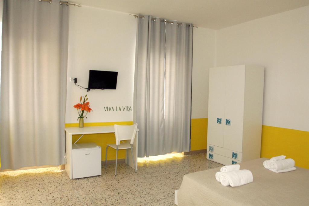 Habitación con 2 camas, escritorio y TV. en Rooms Plaza, en Marina di Camerota