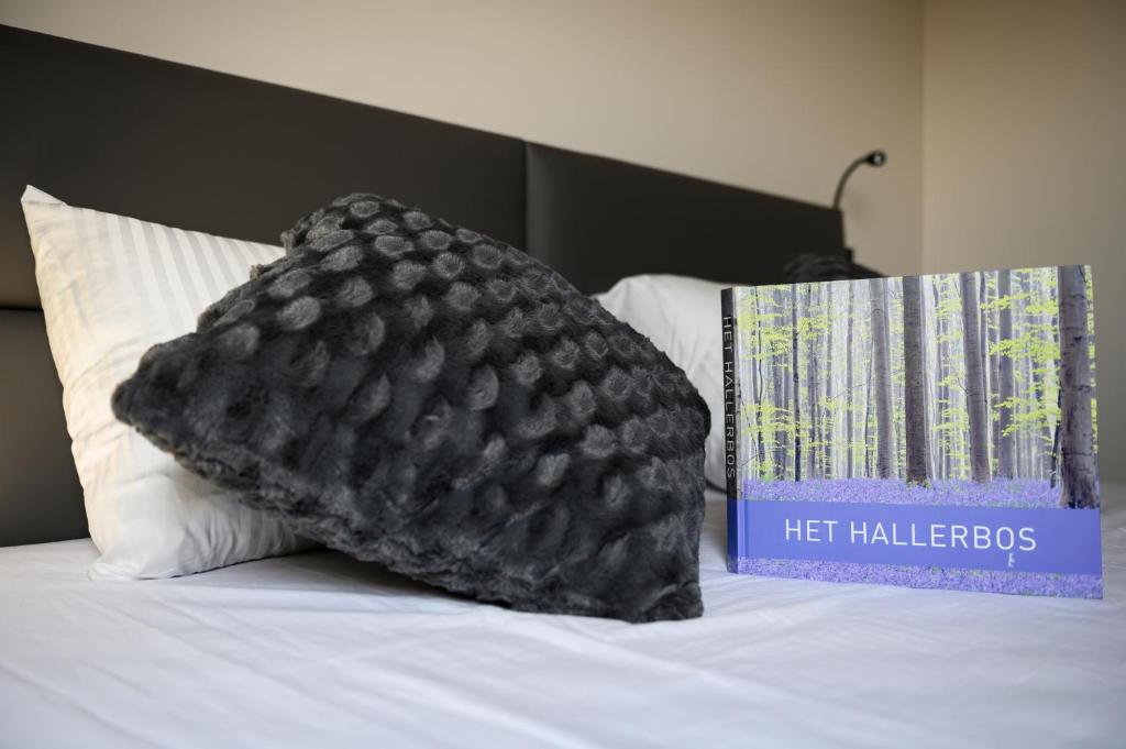 a black pillow sitting on a bed next to a book at B&B Hof ter Kouter in Dworp